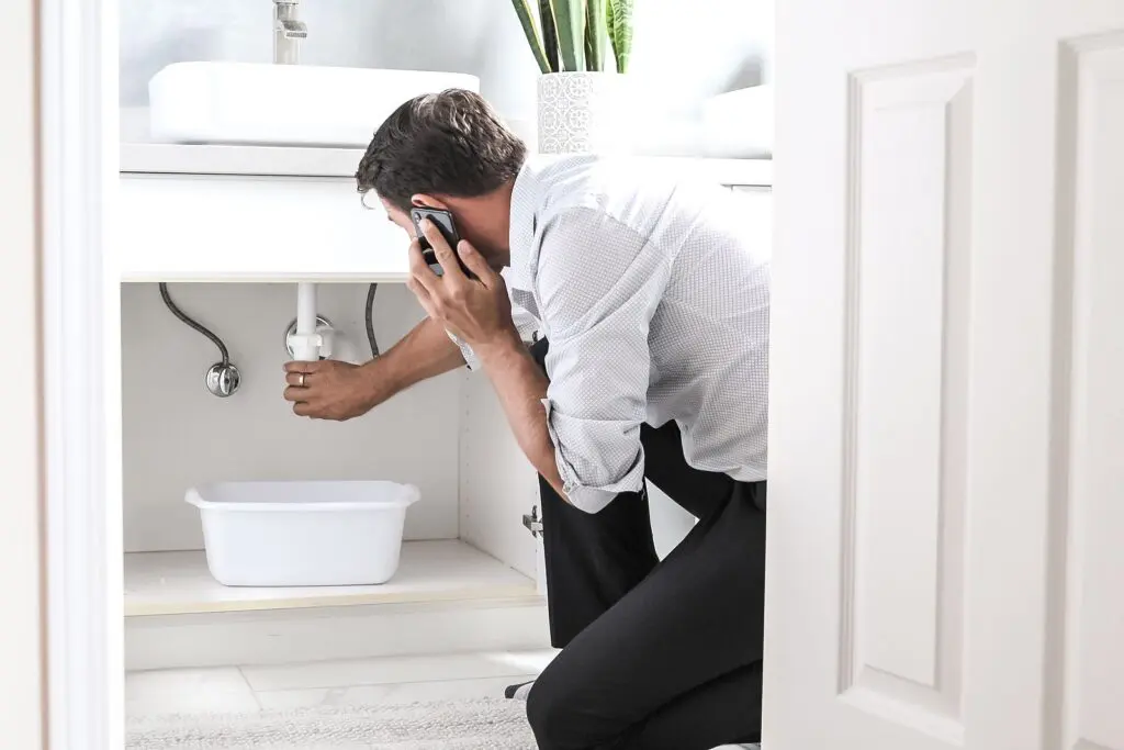 bigstock-Man-Calling-Plumber-In-Front-O-361105207-min