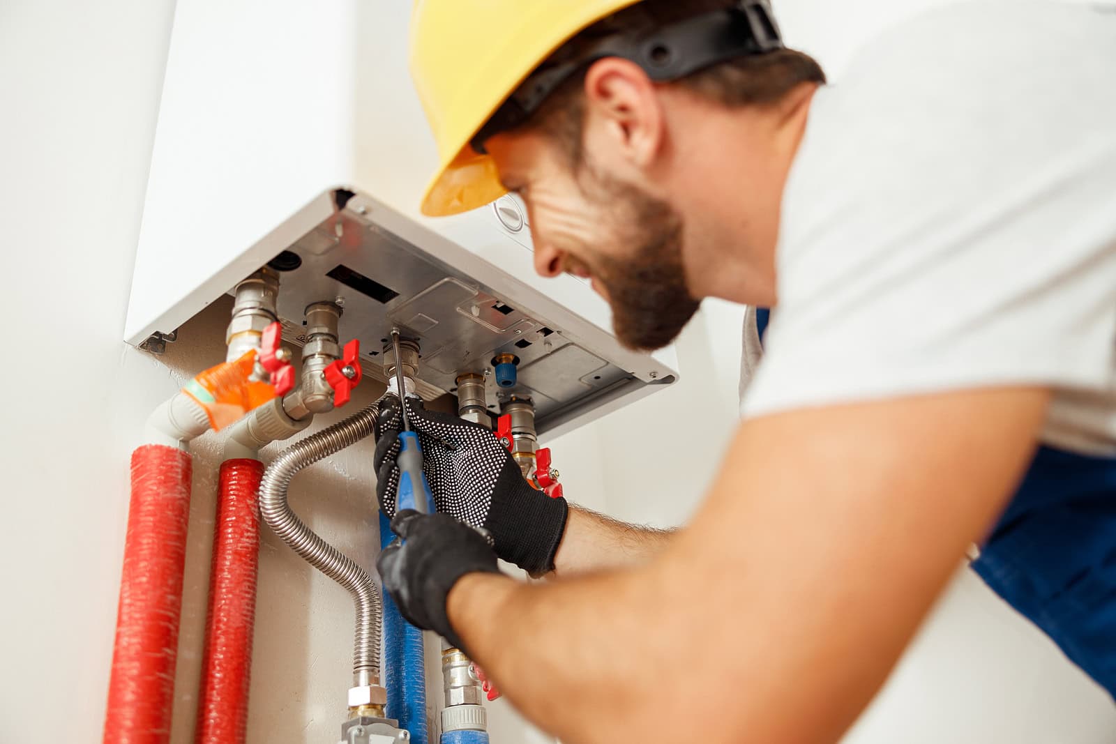 Closeup of plumber using screwdriver while fixing boiler or wate