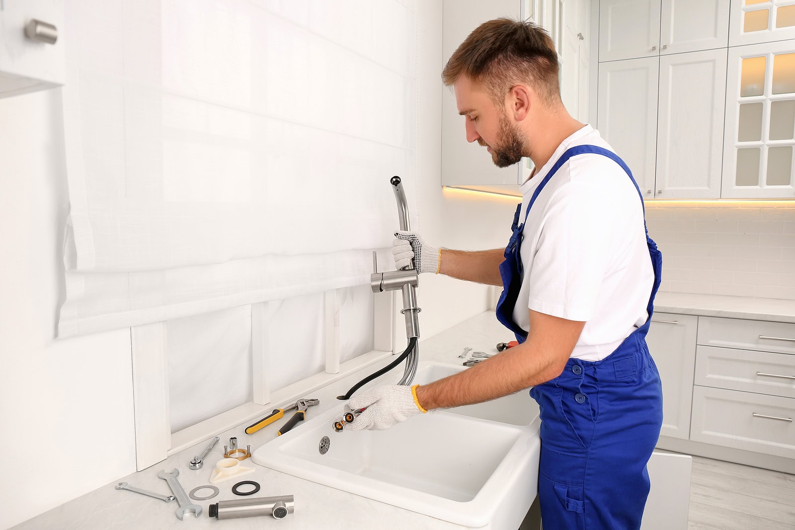 Professional plumber repairing water tap in kitchen
